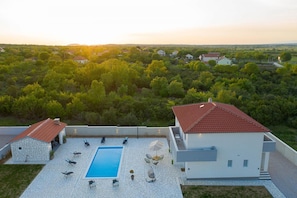 A modern house with a swimming pool, outdoor seating, and a view of a green landscape. - Villa Lidija Zadarvillas (Polaca)