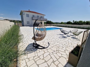 A rooftop pool area with a hanging chair, two lounge chairs, and a potted plant. - Villa Lidija Zadarvillas (Polaca)
