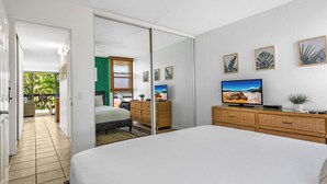 A bedroom with a bed, a TV, a dresser, and a sliding door leading to a balcony. - Modern Beautiful Renovated Maui Vista 3220 (Kihei)
