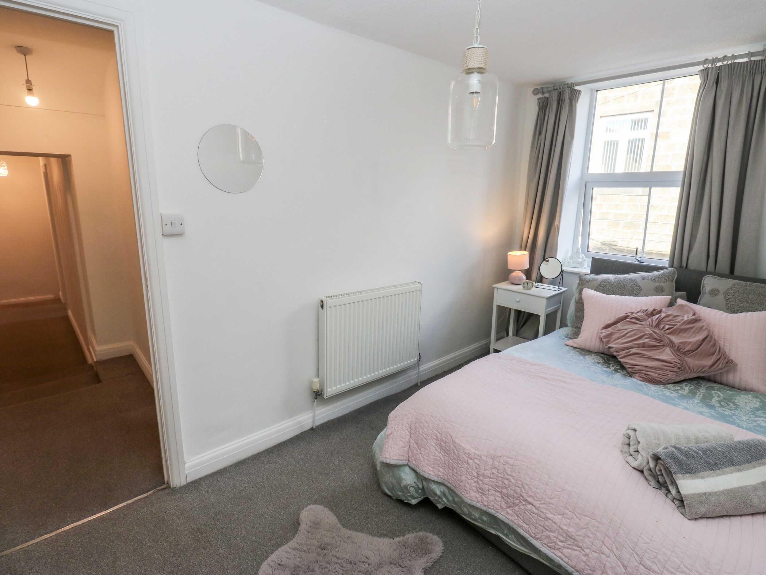 A bedroom with a bed, bedside table, lamp, and a window with curtains.
