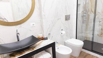 Une salle de bain moderne avec un meuble-lavabo en marbre, un bidet, des toilettes et une douche à parois de verre.