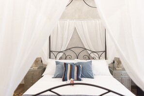 A bed with a canopy, pillows, a bedside table, and a nightstand. - B&B I MORI (Catania)