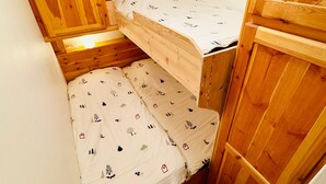 Una piccola stanza in legno con due letti a castello, uno sopra l'altro.