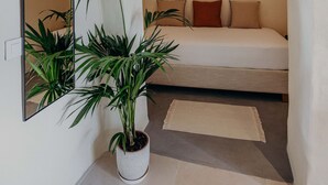 Een slaapkamer met een bed, een spiegel en een kamerplant.