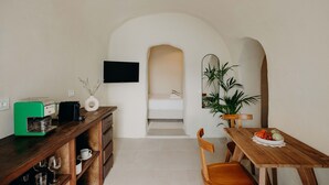 Een compacte kamer met een kitchenette, een bed, een eethoek en een aan de muur bevestigde televisie.