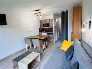 A modern living room with a grey sofa, a wooden dining table, and a small coffee table.
