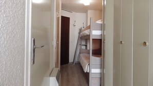 A narrow hallway with bunk beds and a door on the right.