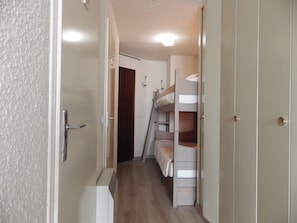 A narrow hallway with bunk beds and a door on the right.