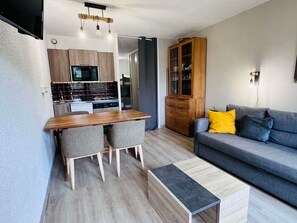 Una cocina moderna con zona de comedor, un sofá gris y un armario de madera.
