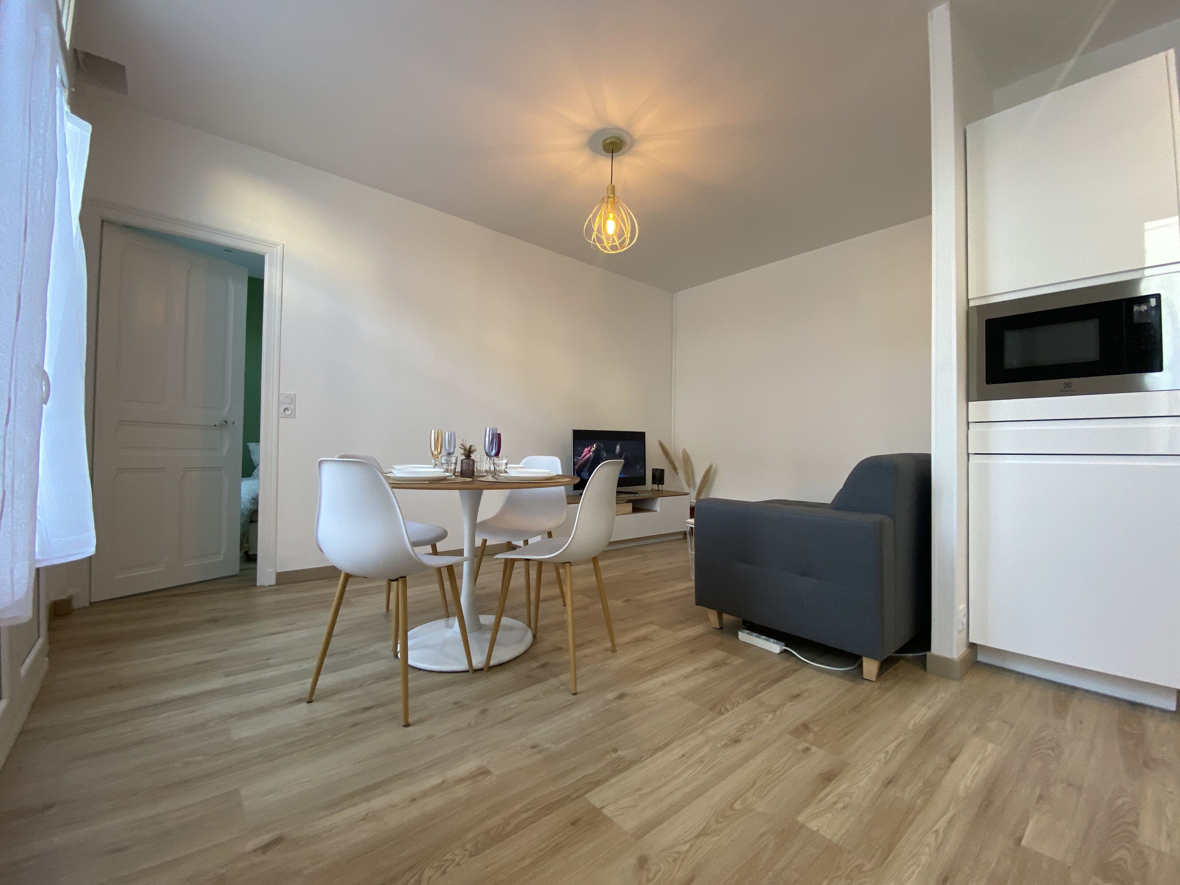 A modern living space with a dining area, a gray sofa, and a built-in microwave.