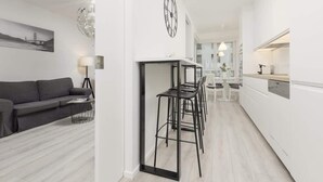 Un espace de vie et de salle à manger moderne, à aire ouverte, comprenant un canapé, une table à manger, des chaises et une cuisine en arrière-plan.