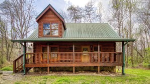 A log cabin with a balcony, a green roof, and a wooden deck. - Convenient Pet friendly Pigeon Forge 2 Bedroom Internet-Hot Tub-Blackberry Ridge (Pigeon Forge)