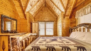 A log cabin bedroom with a bed, a mirror, and a window. - Convenient Pet friendly Pigeon Forge 2 Bedroom Internet-Hot Tub-Blackberry Ridge (Pigeon Forge)