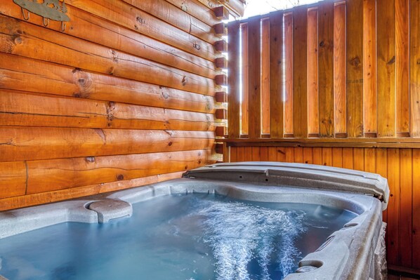 A hot tub inside a log cabin with wooden walls and a wooden fence.