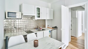 A modern kitchen with white cabinets, a stainless steel backsplash, and a marble countertop. - Charmant T2 à 5 Minute de Paris (Issy-les-Moulineaux)