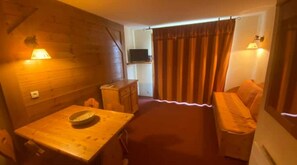Cozy single room with a small table, single bed, and TV.