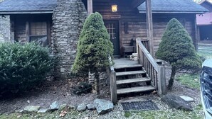A rustic log cabin with a stone chimney, a wooden porch, and a gravel driveway. - Mt. Cabin near water falls, skiing, shopping
Peaceful creek location




 (Maggie Valley)