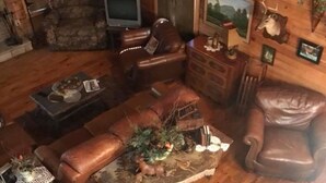 A rustic cabin interior with a leather sofa, a wooden coffee table, and a television. - Mt. Cabin near water falls, skiing, shopping
Peaceful creek location




 (Maggie Valley)