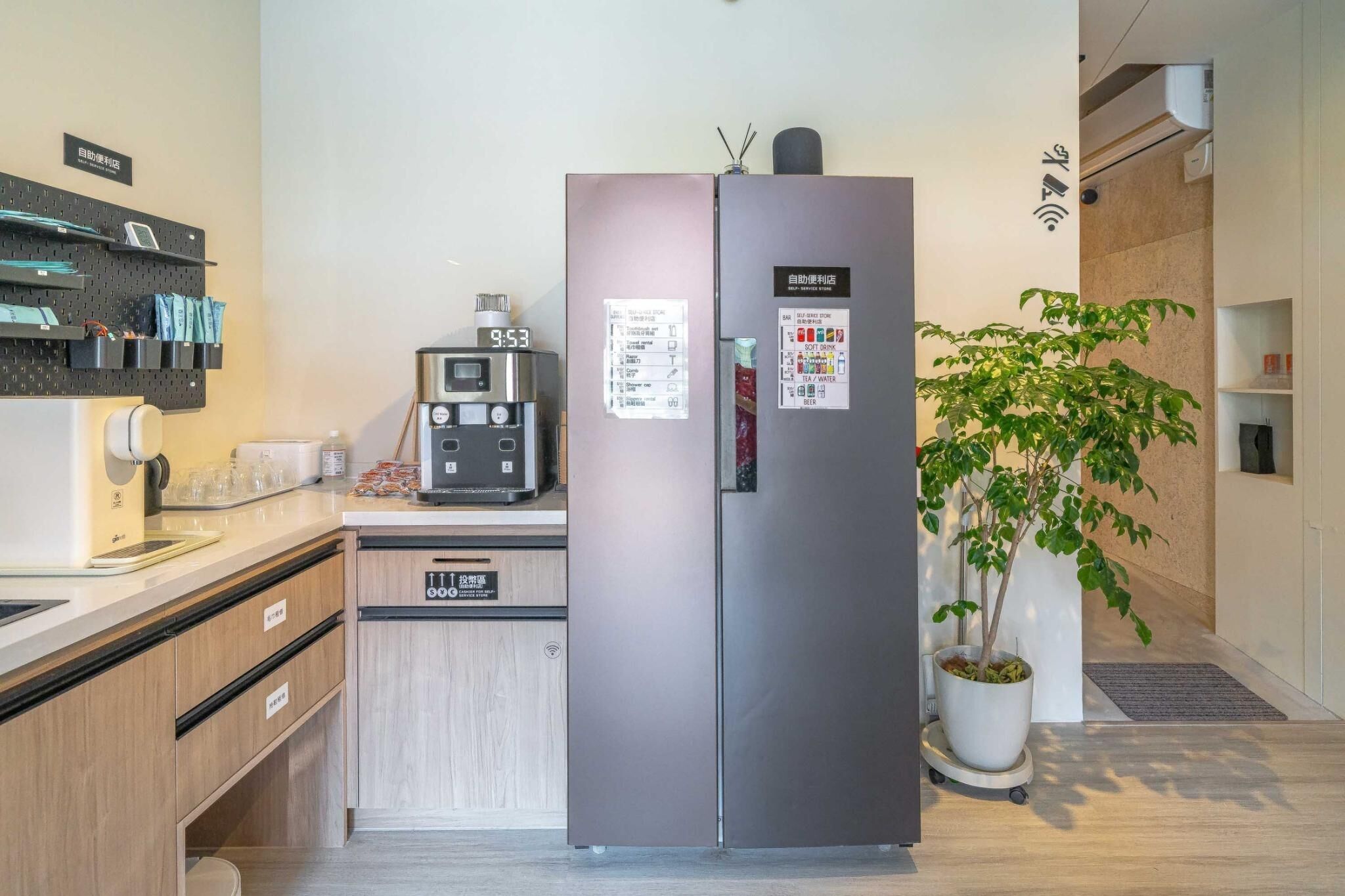 A modern kitchen with a stainless steel refrigerator, a coffee machine, and a wall-mounted pegboard with kitchen tools.