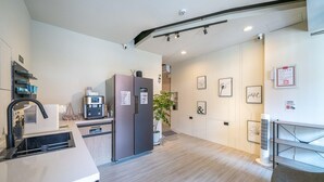 A modern kitchen with a built-in oven, a refrigerator, and a sink. There is a plant and a fan in the room. - Times Inn - Tainan  (Tainan)