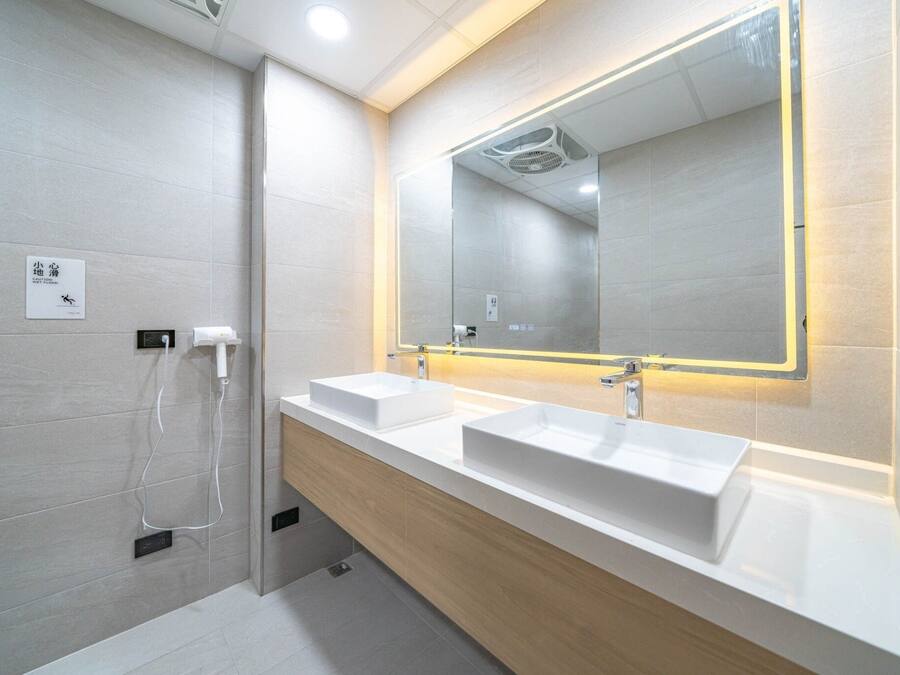 A modern bathroom with two sinks, a large mirror, and a shower area.