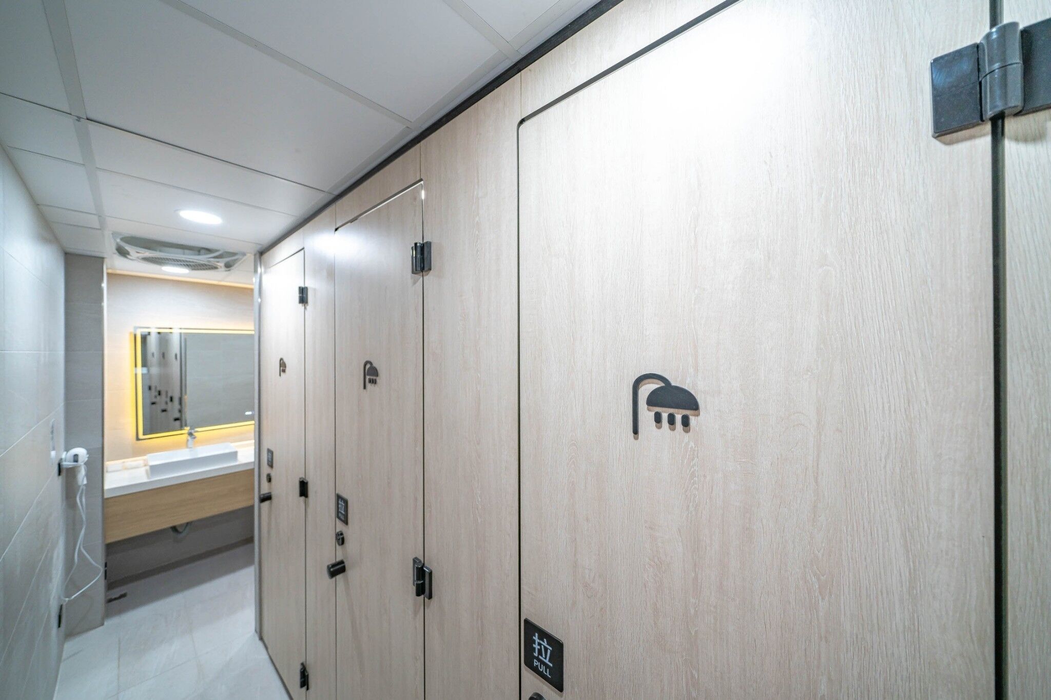A hotel corridor with wooden lockers, a sink, and a mirror.