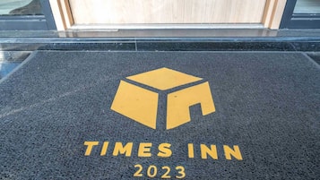 Un paillasson A Times Inn 2023, orné du logo et du nom de l’établissement.