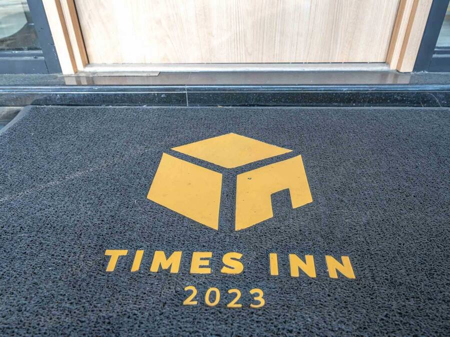 Un paillasson A Times Inn 2023, orné du logo et du nom de l’établissement.