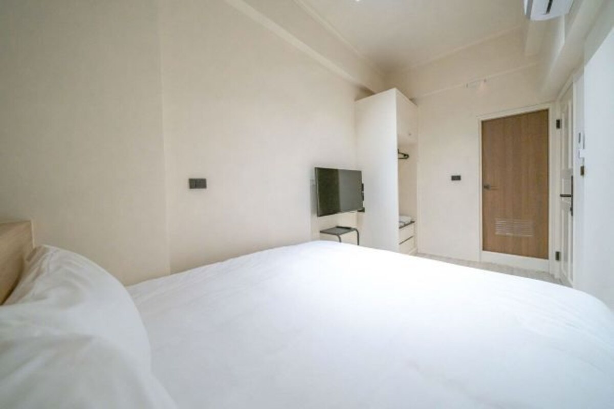 A hotel room with a large bed, a television, and a wooden door.