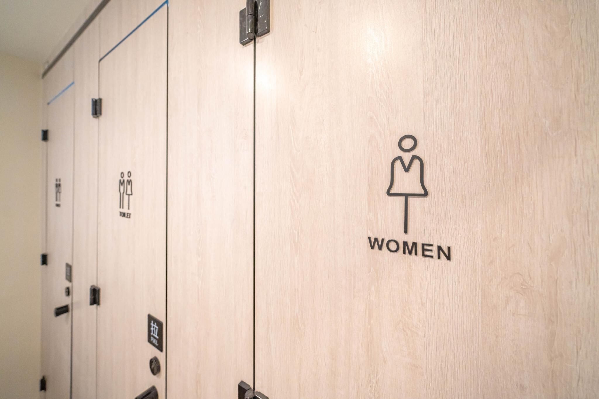 A row of wooden doors with symbols indicating women's and men's restrooms.
