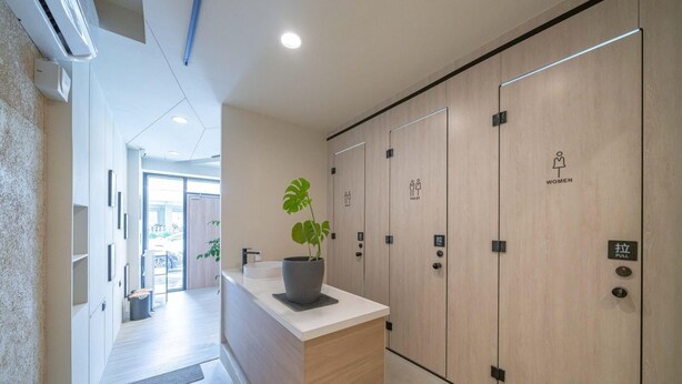 A modern hotel lobby with a reception desk, a potted plant, and wooden lockers for men and women. - Times Inn - Tainan  (Tainan)