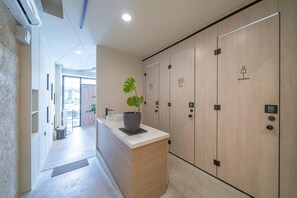A modern hotel lobby with a reception desk, a potted plant, and wooden lockers for men and women. - Times Inn - Tainan  (Tainan)
