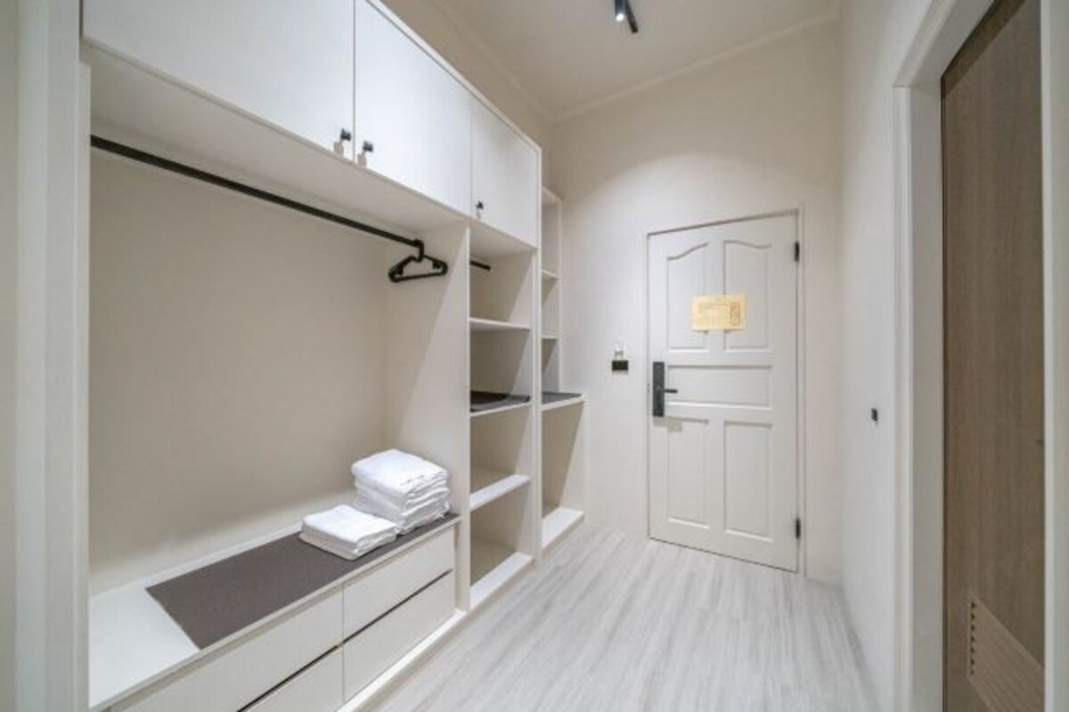 A hallway with a white wardrobe, a door with a note, and a light-colored floor.