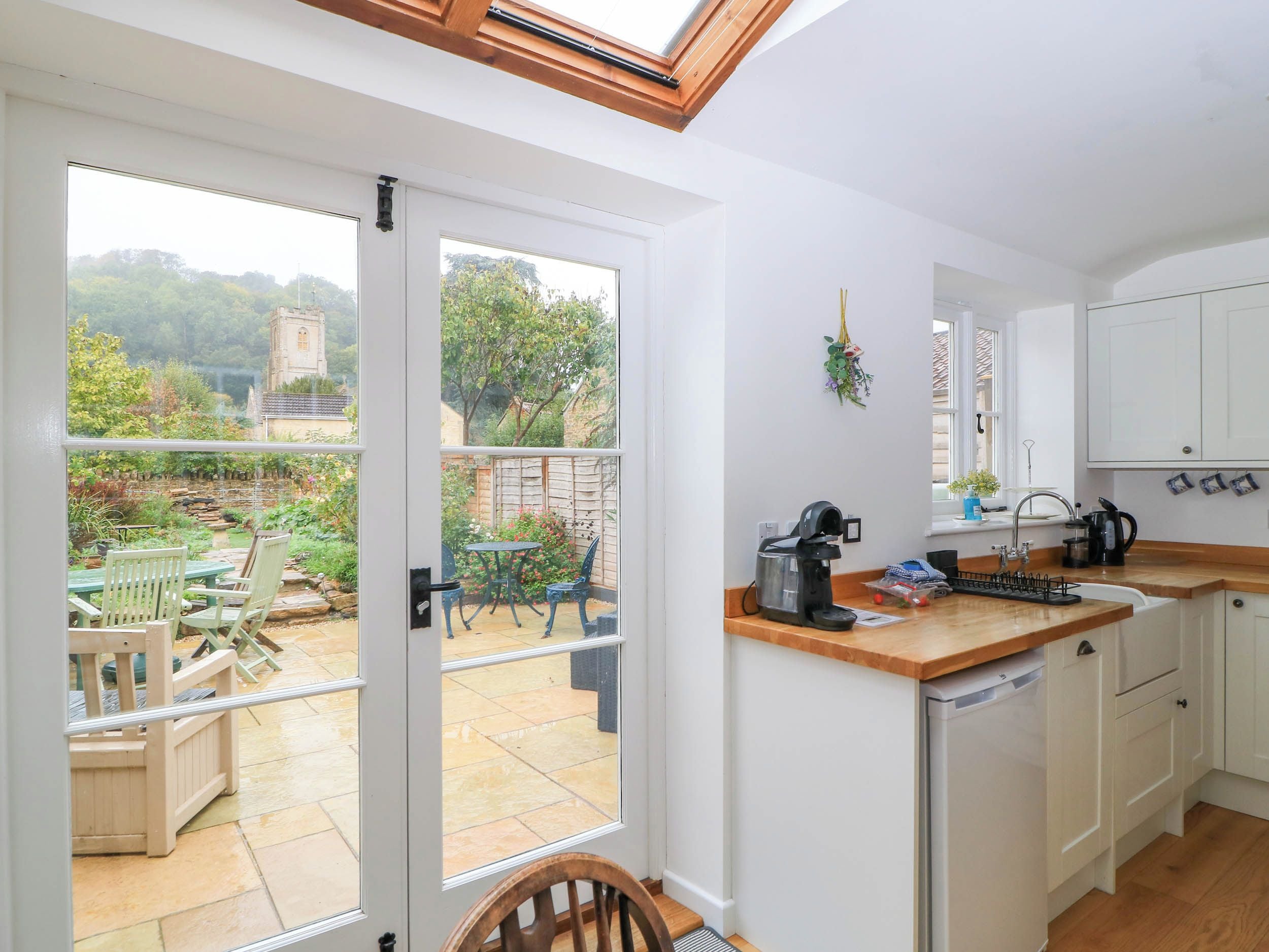 A kitchen with a view of a garden, a coffee machine, and a sink.