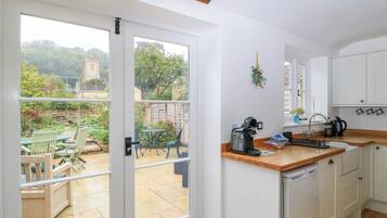 A kitchen with a view of a garden, a coffee machine, and a sink.