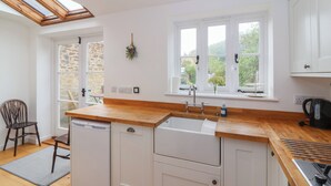 A modern kitchen with white cabinetry, a wooden countertop, a built-in dishwasher, and a gas stove.