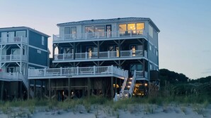 A multi-level beachfront house with balconies and a staircase leading to the upper levels. - Admirals Lodge | Pool & Hot tub | Games | Oceanfront (Oak Island)
