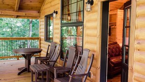 Een houten vakantiehuisje met een terras, een ronde tafel en vier stoelen.