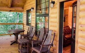 Cozy cabin with a round table, leather sofa, and glass door leading to an outdoor area.