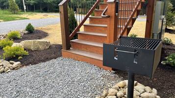 A wooden staircase with a metal grill attached to a post, surrounded by gravel and rocks.
