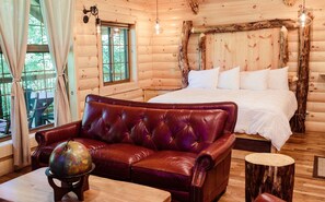 Relax in this charming cabin room with a plush sofa, round table, and a large bed with crisp linens.