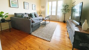 Una sala de estar con un sofá gris, una mesita de centro, un televisor y una planta.