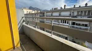 Un balcón con baranda de metal que da a una hilera de edificios con múltiples ventanas y balcones.
