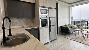Een moderne keuken met een inbouwoven, magnetron en koelkast. Een groot raam biedt uitzicht op de stad.
