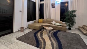 A modern living room with a sectional sofa, a coffee table, and a large window with curtains. - Prayer mountain Cove -tranquility and cosiness at its best. Incredible views! (Kampala)