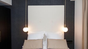 Una habitación de hotel moderna con una cama grande, dos mesitas de noche y un cabecero con iluminación integrada.