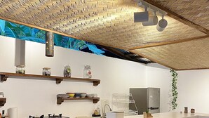Une cuisine moderne dotée d’un long comptoir, d’appareils électroménagers intégrés et d’un plafond orné d’un motif tissé.