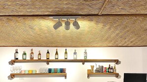 Un espace bar avec des étagères où sont exposées des bouteilles, des verres et un téléviseur.