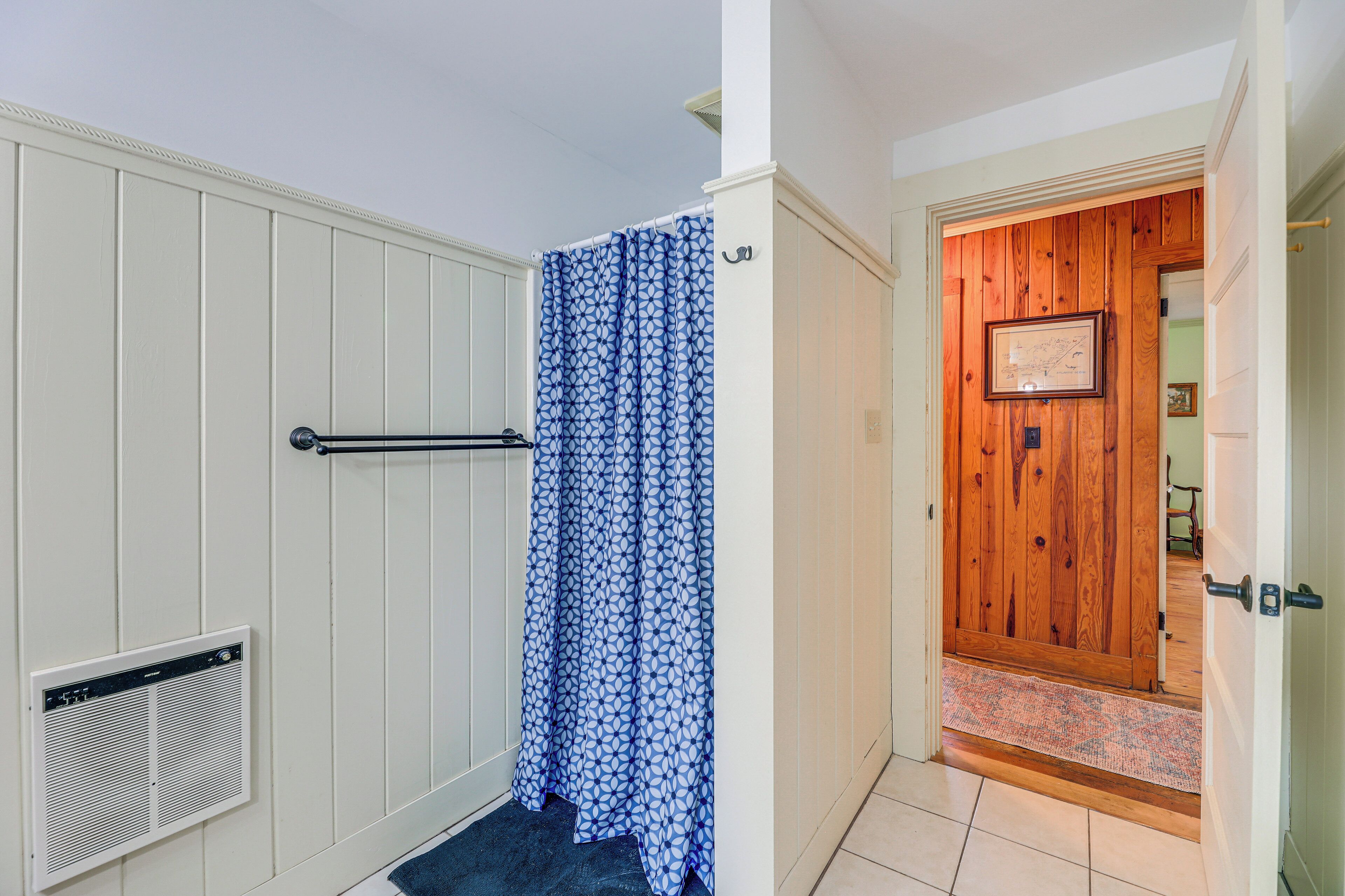 A bathroom with a shower, a towel rack, and a vent.