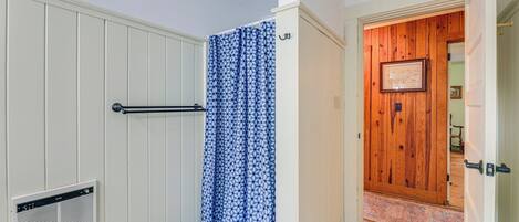 A bathroom with a shower, a towel rack, and a vent.